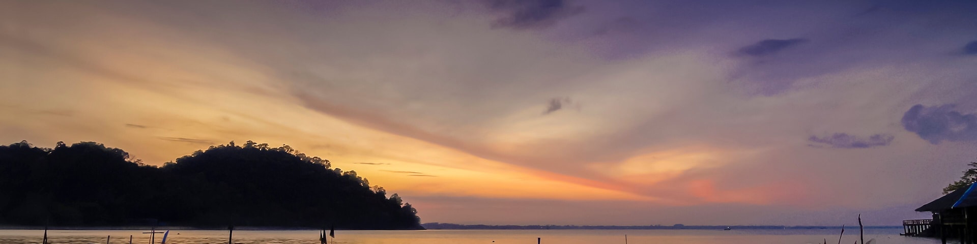 view seaside morning of fishing boats floating in the sea with orange sun light and cloudy sky background, sunrise at Mu Ko Phetra National Park, pak nam, la-ngu district, Satun, Thailand.