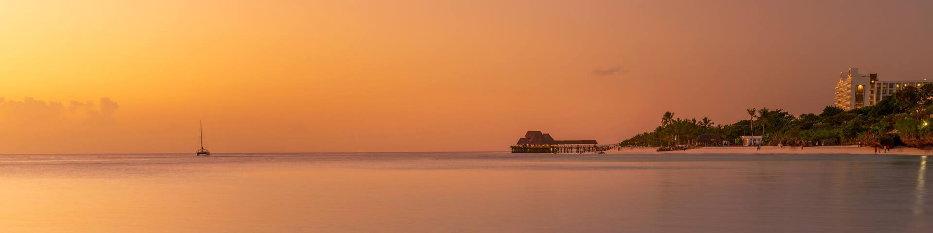 Panorama of Zanzibar shore with sandy beach,luxury resort and thatch stilt house restaurant at sunset. Summer travel in Zanzibar, Africa,Tanzania.