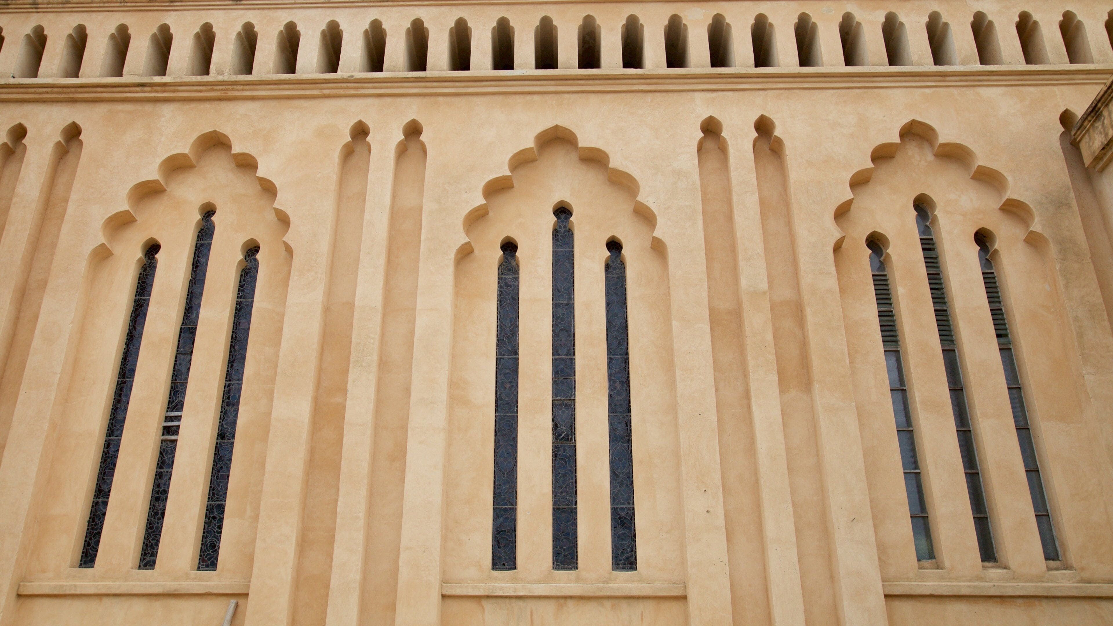 Une façade d’immeuble ornée de trois fenêtres en arc et de moulures décoratives.