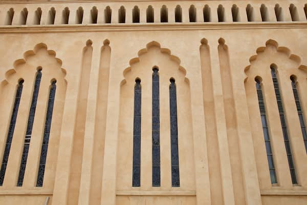 Une façade d’immeuble ornée de trois fenêtres en arc et de moulures décoratives.