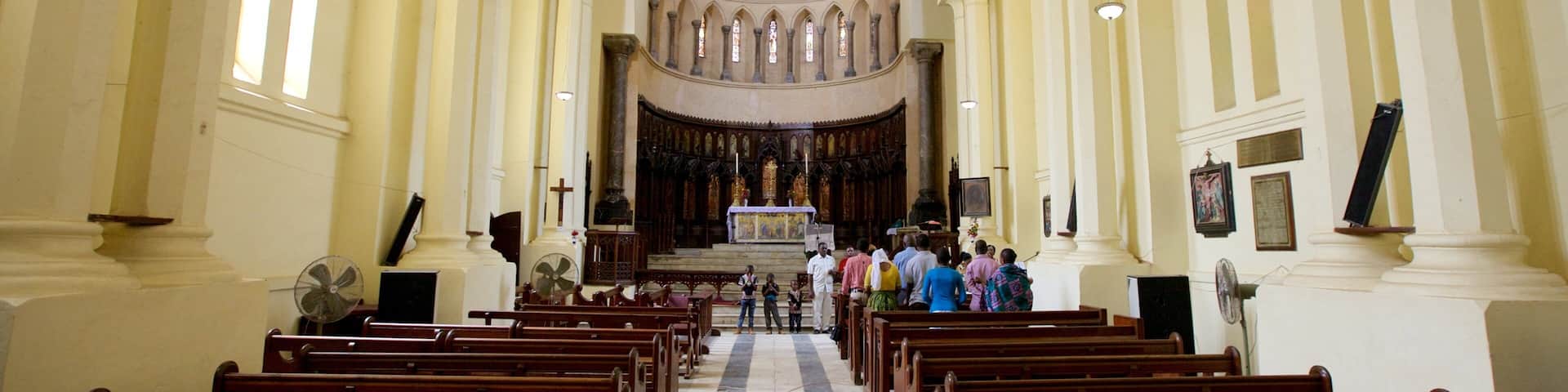 A church interior with rows of wooden pews, a central aisle leading to an altar, and stained glass windows.