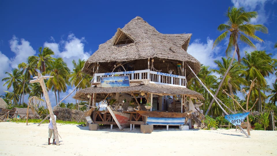 A beachside restaurant with a thatched roof and a signboard advertising local cuisine and fresh drinks.