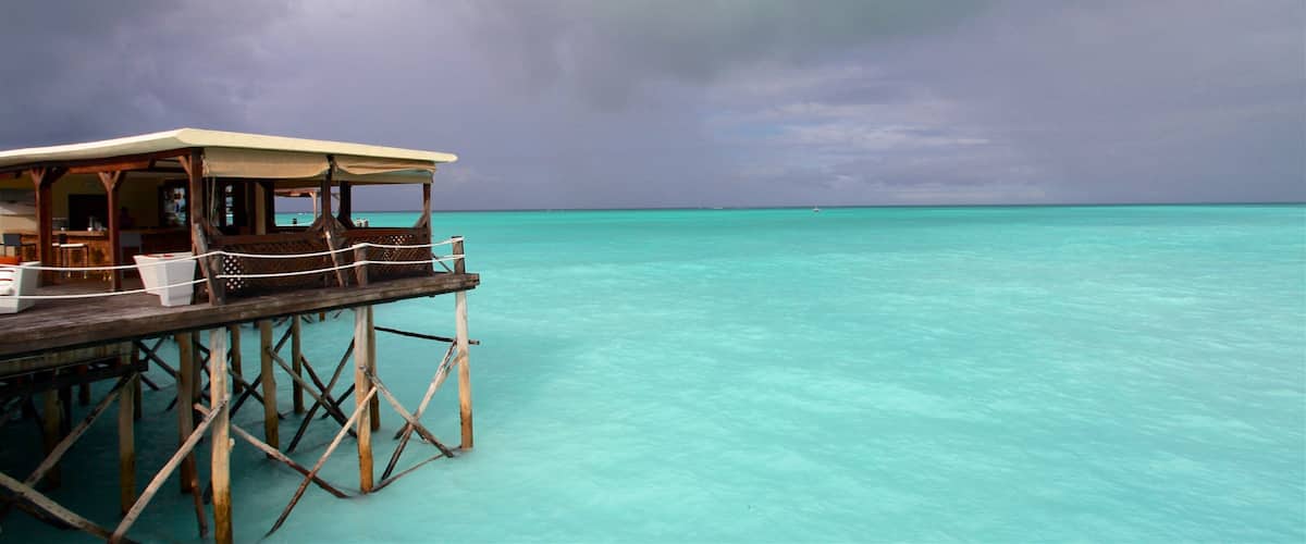 A wooden overwater structure with a covered seating area overlooking turquoise waters.