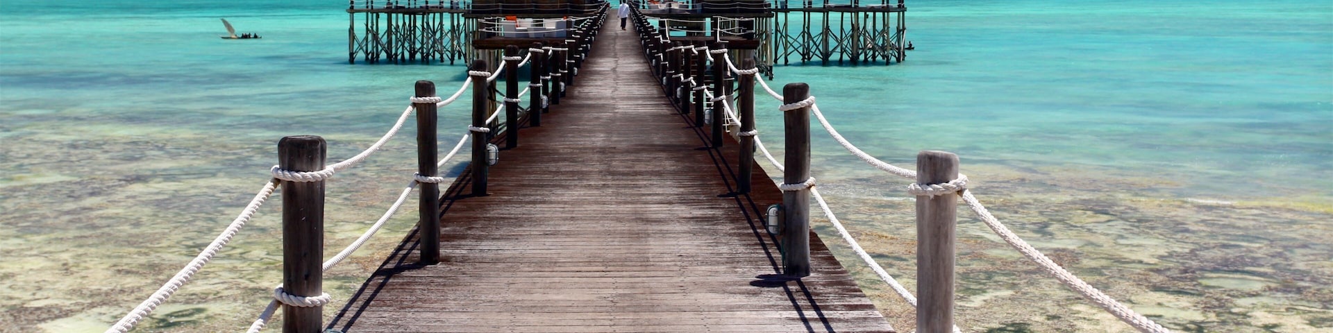 A wooden pier leading to overwater bungalows with turquoise water.
