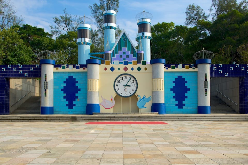 A castle-like structure with a clock, swan decorations, and a tiled entrance.