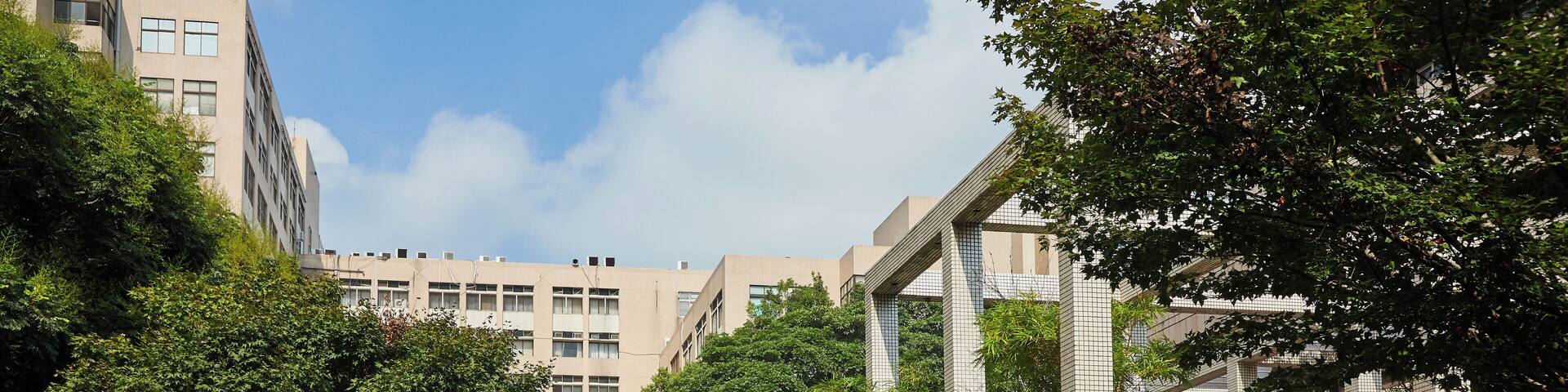 A modern urban street with buildings, greenery, and a person walking.