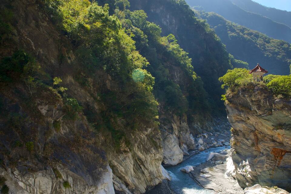 A canyon with a river, rocky cliffs, and a pagoda on a cliff edge.