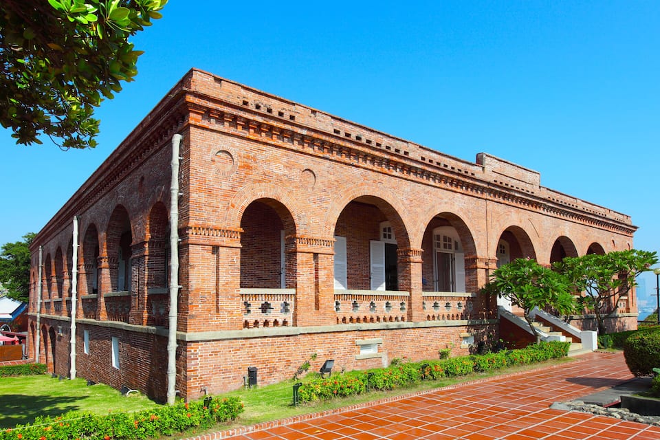 A historic brick building with arched windows and a tiled walkway.