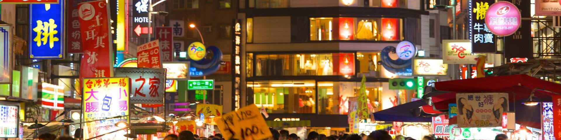 A crowded street at night with illuminated signs and billboards in a foreign language.