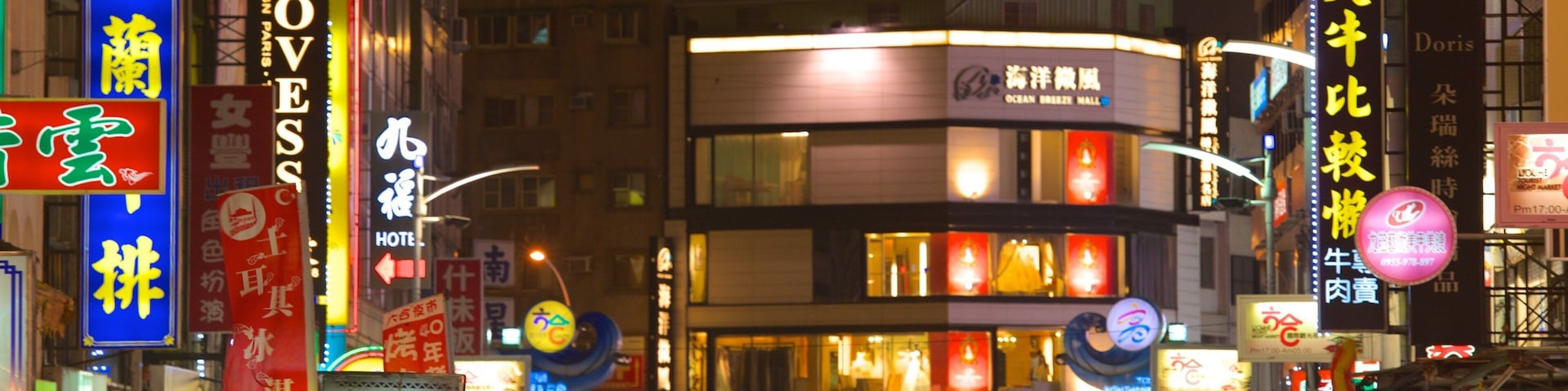 A crowded street at night with illuminated signs and billboards in a foreign language.
