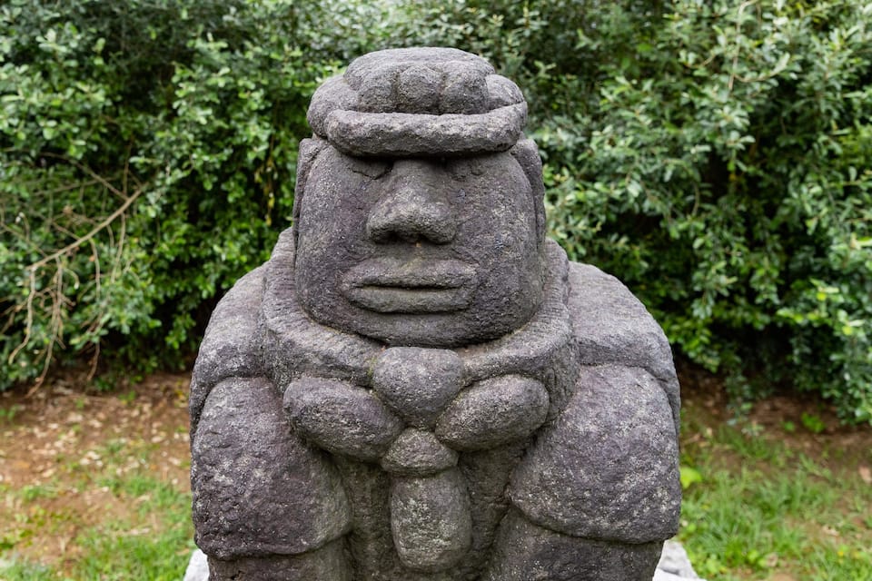Une statue de pierre coiffée d’un chapeau et portant une écharpe.