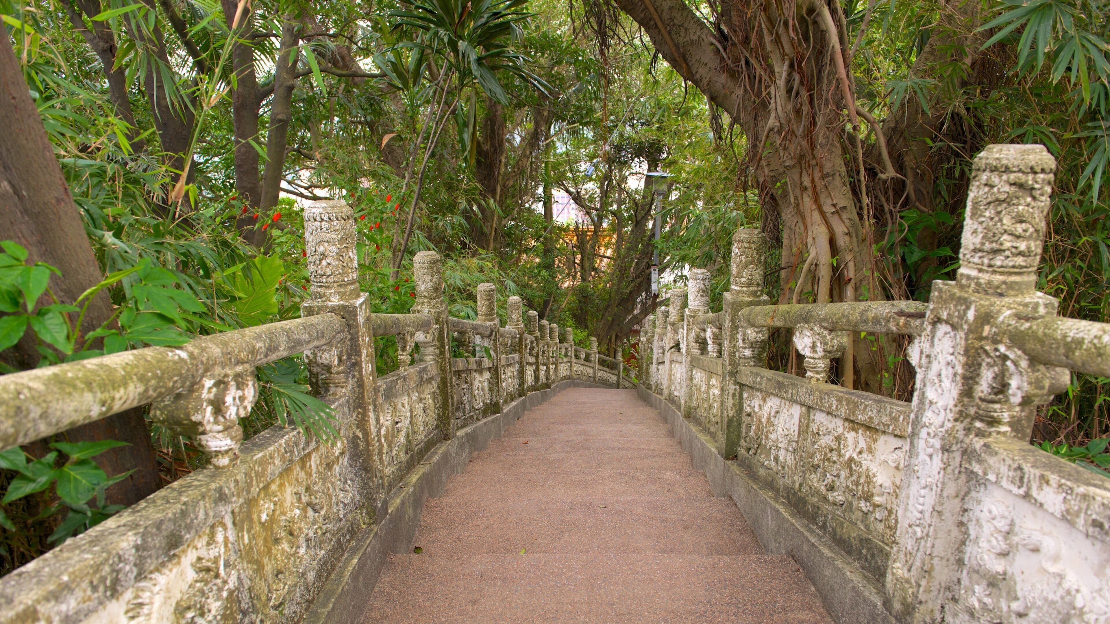 A stone bridge with ornate railings surrounded by lush greenery.