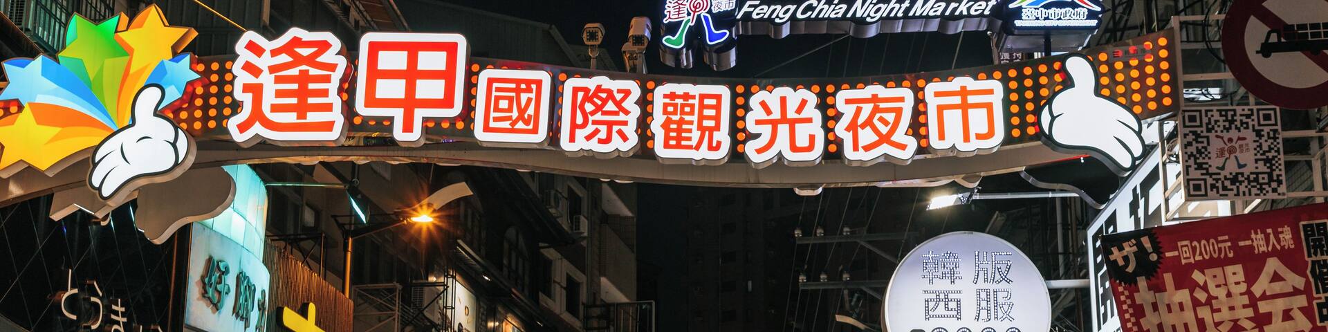 A bustling street market with illuminated signs and mannequins displaying clothing.