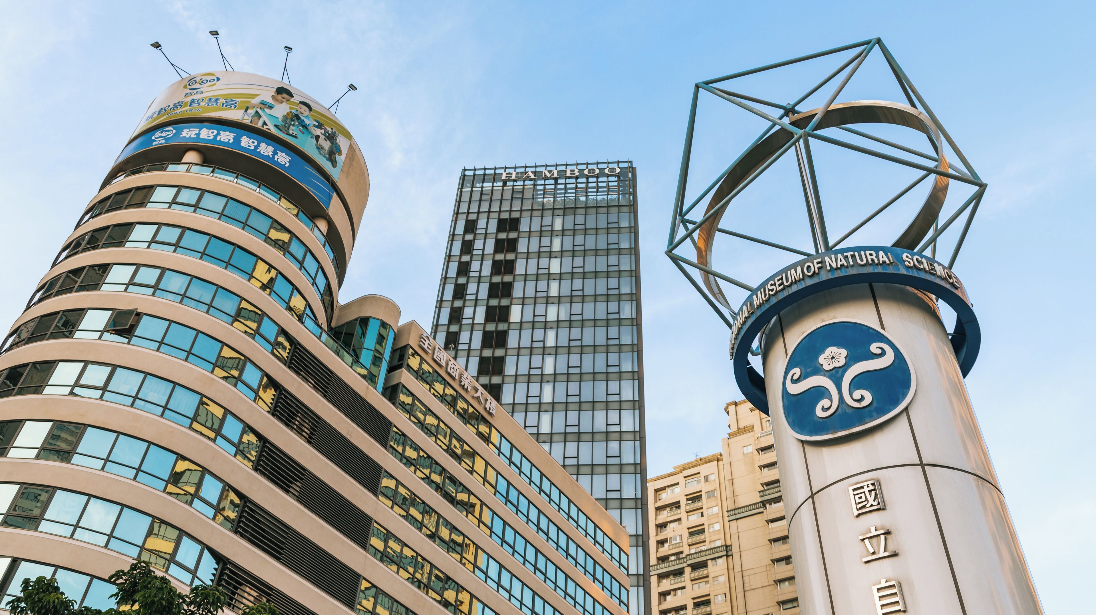 A modern building with a curved facade and a large sign with Chinese characters.