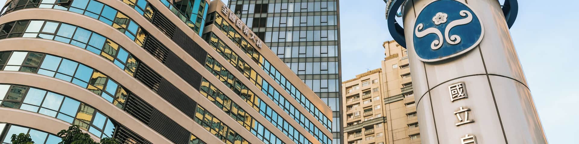 A modern building with a curved facade and a large sign with Chinese characters.