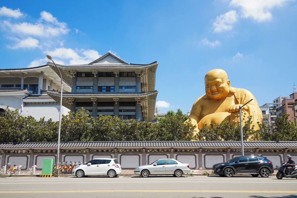 A traditional building with a large golden statue in front.