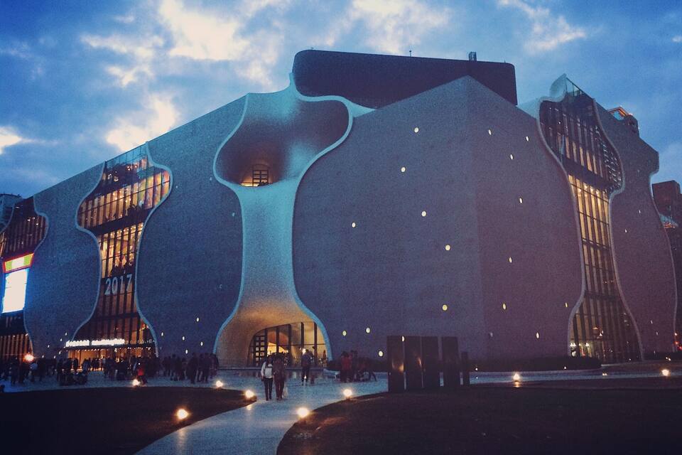 Un edificio de arquitectura moderna con formas orgánicas y ventanas iluminadas.