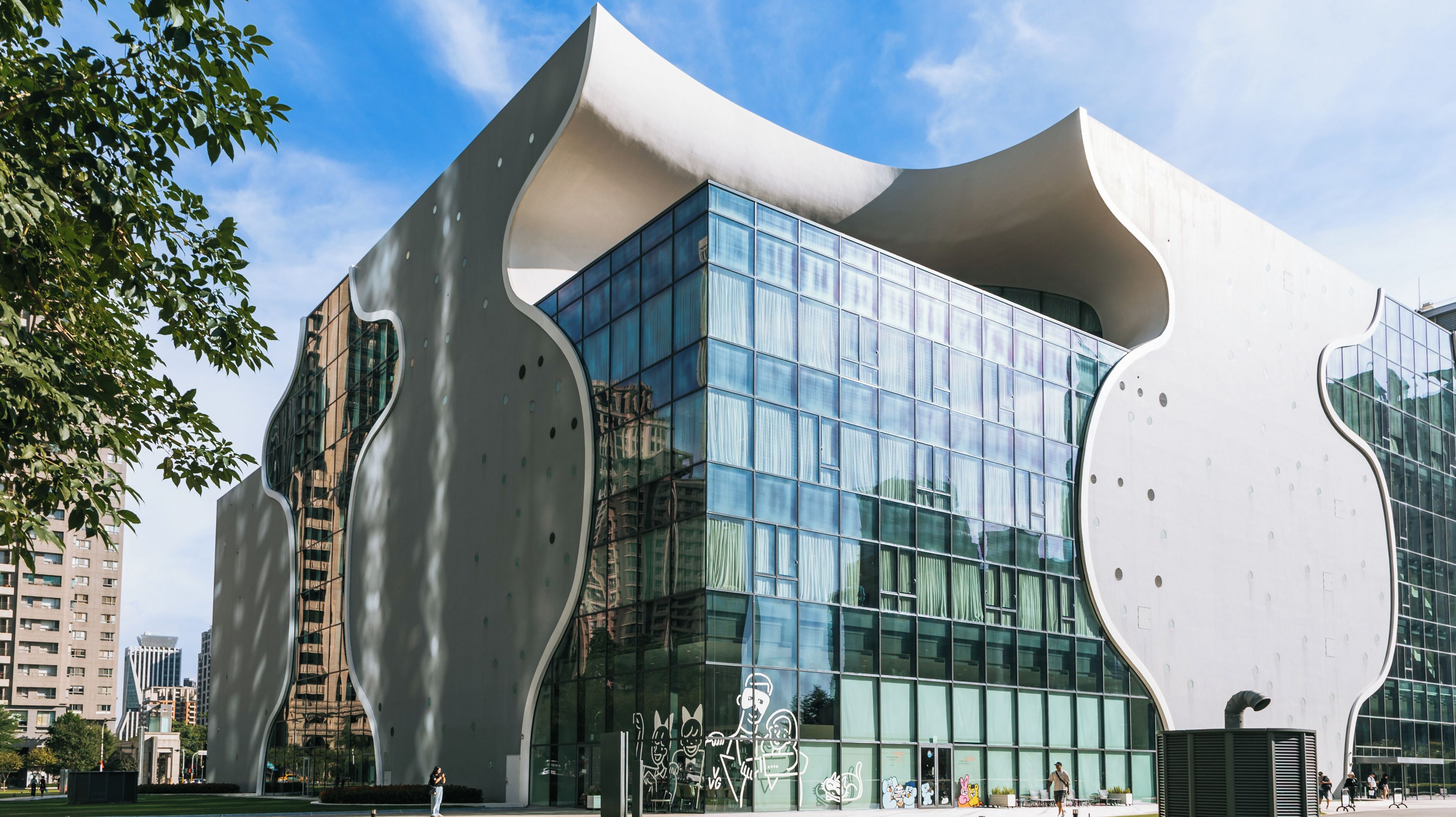 A modern building with large glass windows and unique white architectural features.