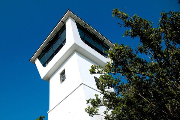 Une tour blanche aux grandes fenêtres, se dressant sur un ciel bleu clair.