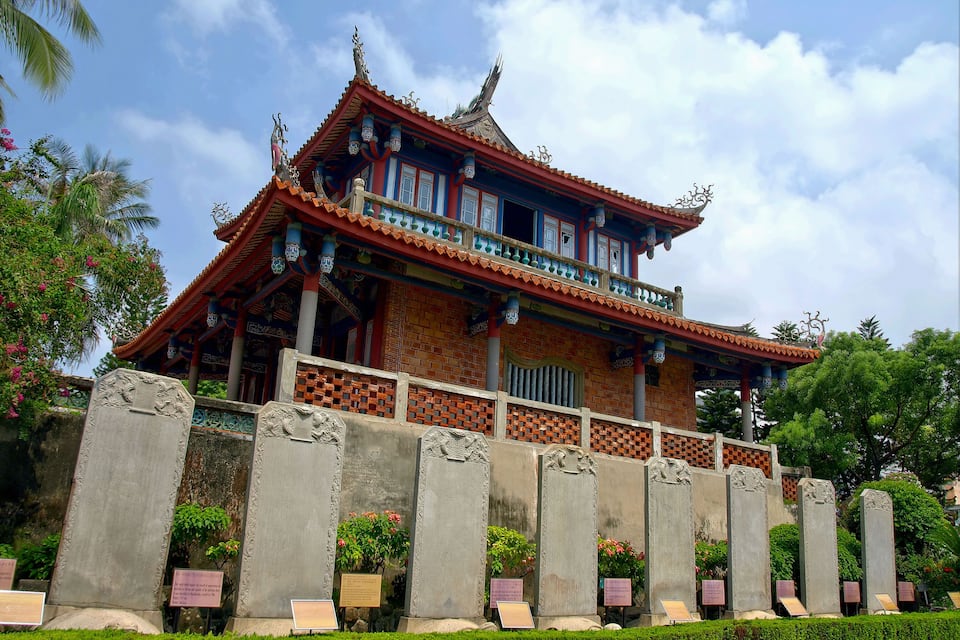 Um edifício tradicional chinês com arquitetura ornamentada, incluindo um telhado com telhas e colunas decorativas.