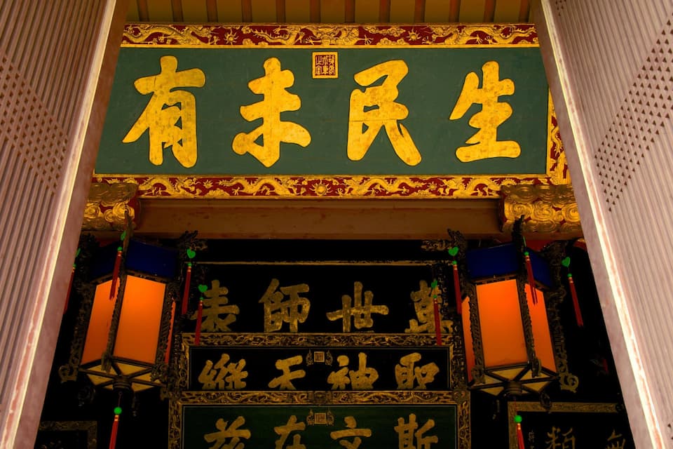 Uma entrada arquitetônica chinesa tradicional com decorações elaboradas e caracteres chineses dourados.