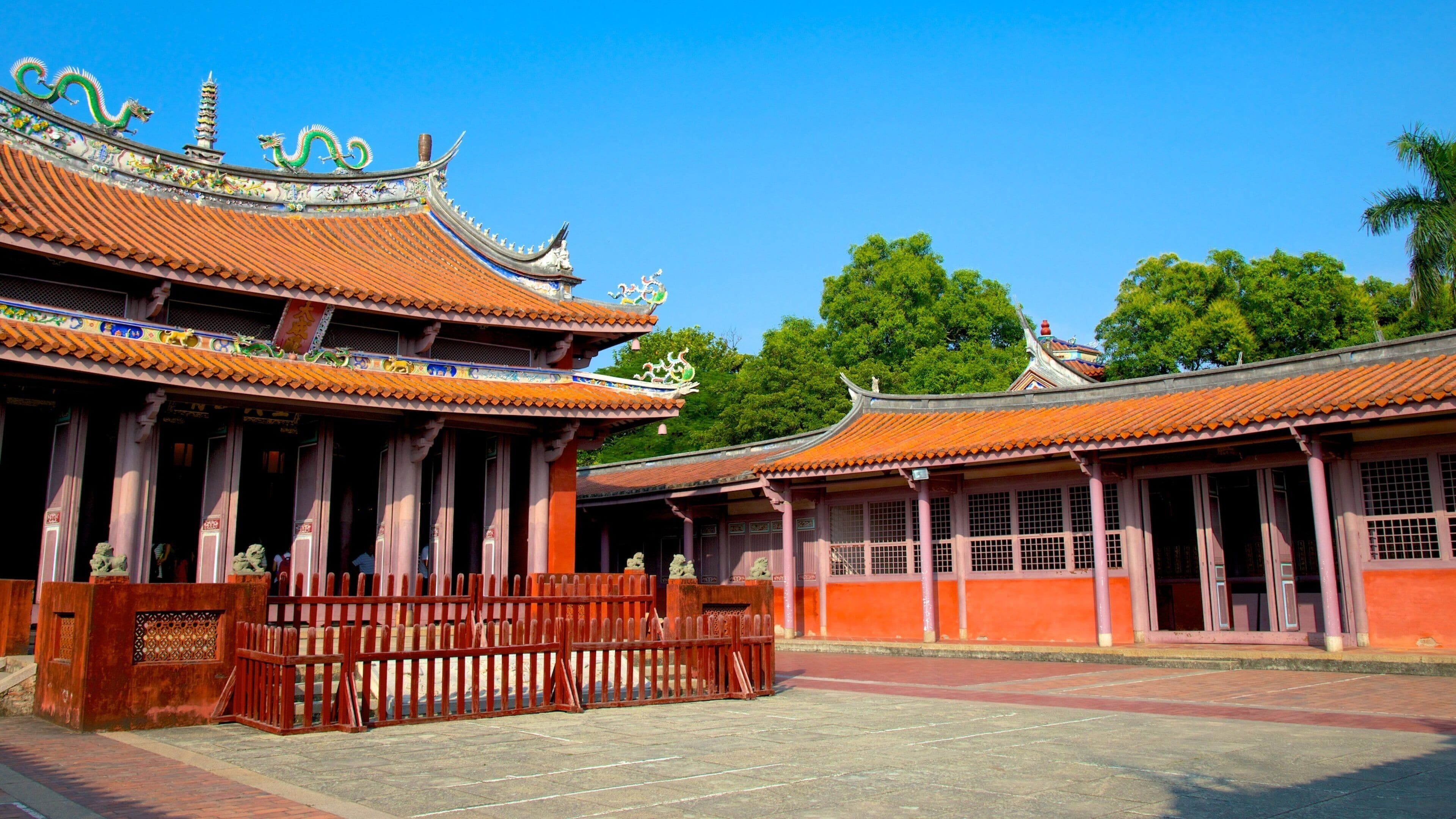 Traditional Chinese architecture with ornate roofs and a wooden fence.