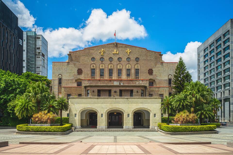 A historic building with arched entrances and a flag on top.