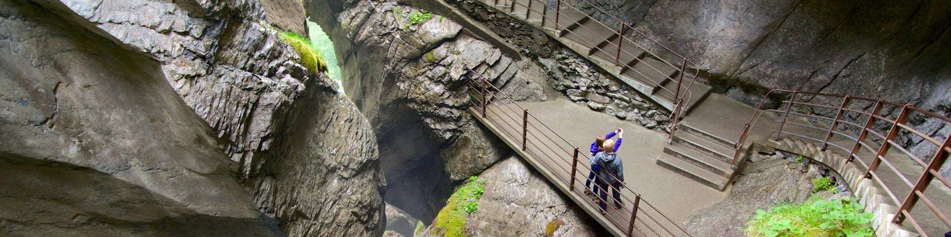 A rocky gorge with a bridge and a waterfall.