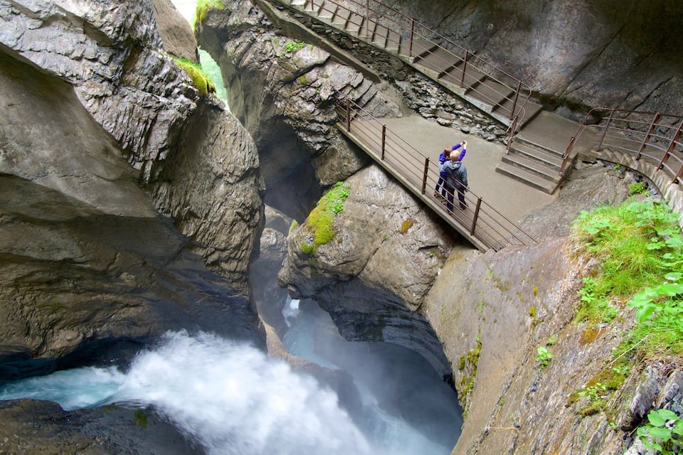 Un desfiladero rocoso con un puente y una cascada.