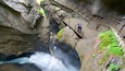 Un desfiladero rocoso con un puente y una cascada.
