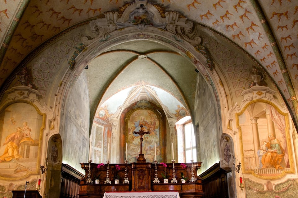 Interior de igreja ornamentado com teto abobadado alto, frescos detalhados e púlpito de madeira.
