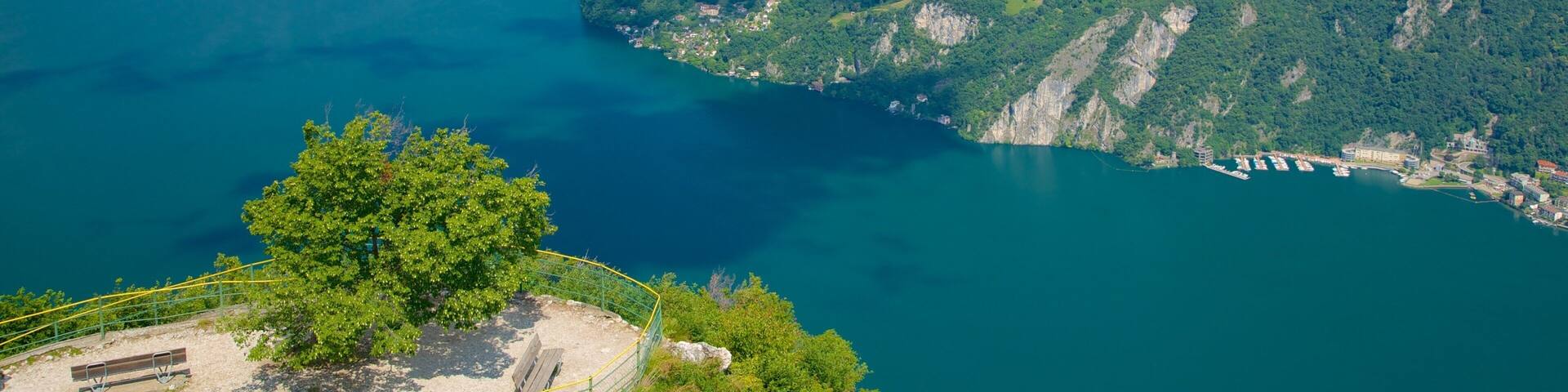 A mountainous landscape with a lake surrounded by lush greenery and a small settlement.