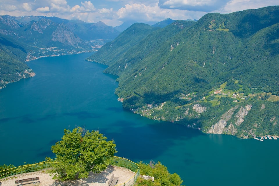 Un paisaje montañoso con un lago rodeado de vegetación exuberante y un pequeño asentamiento.