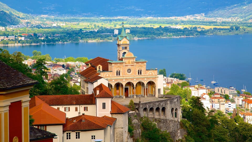 A historic church with a bell tower, surrounded by a lake and mountains.