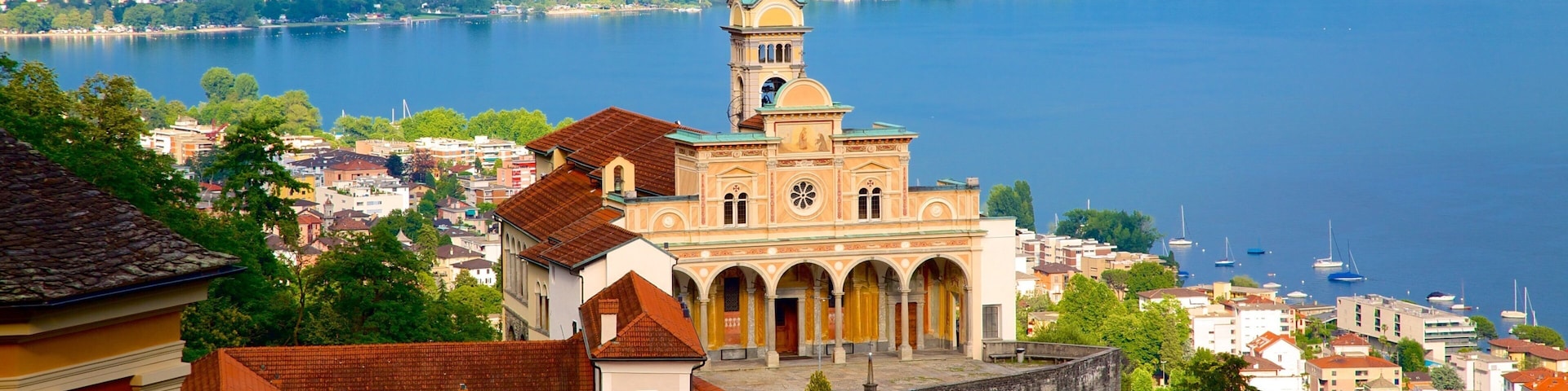 A historic church with a bell tower, surrounded by a lake and mountains.