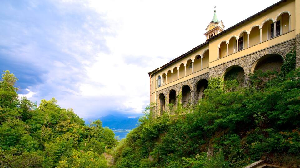 A historic building with arches and a tower, surrounded by lush greenery.