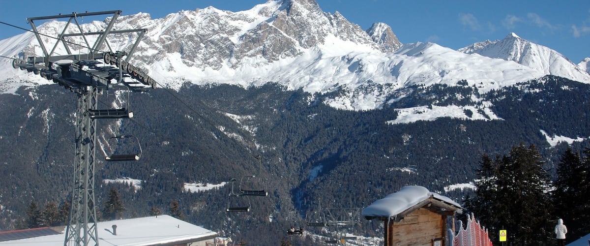 A snow-covered mountain with ski lifts and a wooden cabin.