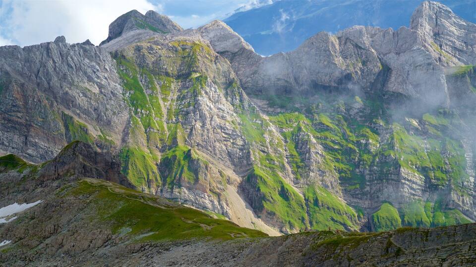 Rugged mountain peaks with green vegetation and a clear sky.