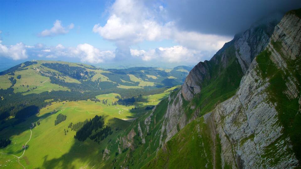 A mountainous landscape with green valleys and rocky cliffs.