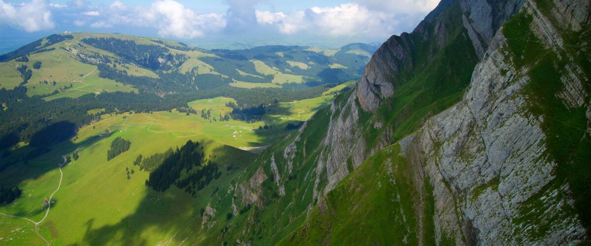 A mountainous landscape with green valleys and rocky cliffs.