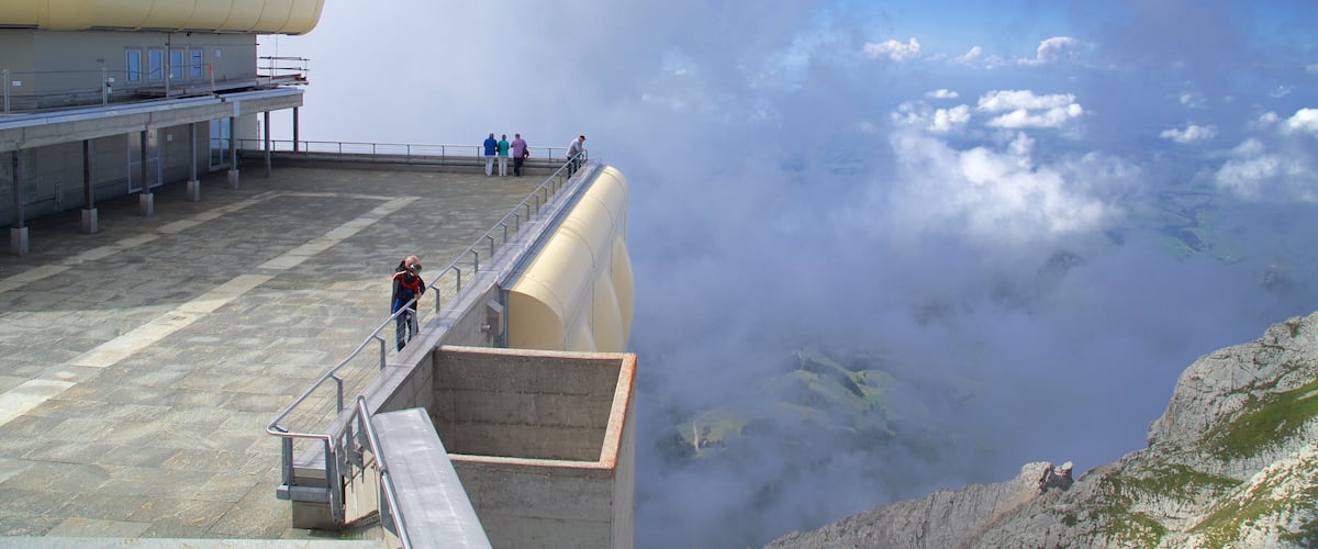 A large industrial structure with a viewing platform overlooking a valley shrouded in clouds.