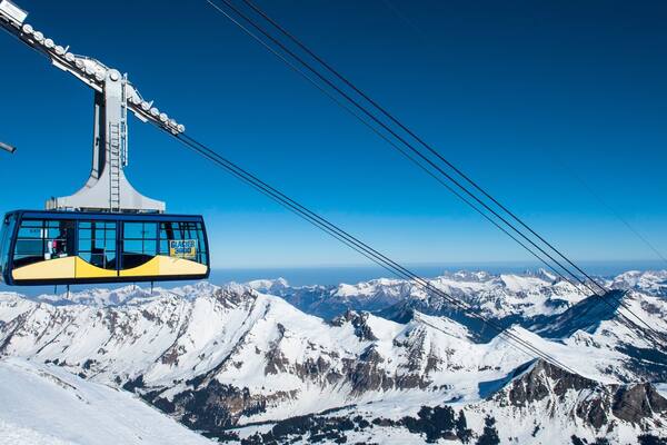 Eine Seilbahn bietet klaren Blick auf schneebedeckte Berge und einen blauen Himmel.