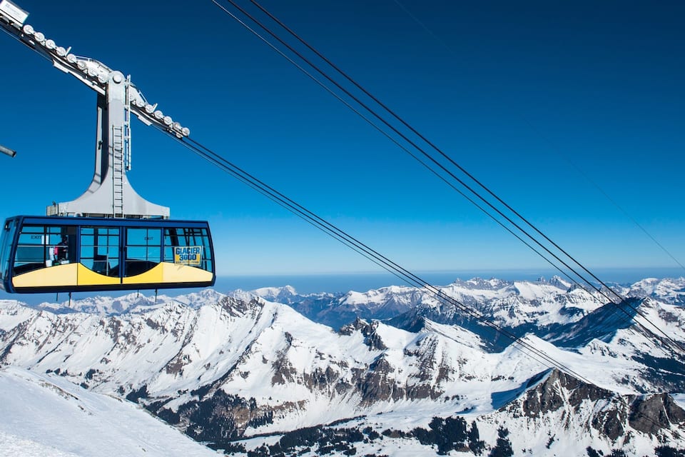 Un teleférico ofrece vistas despejadas de montañas nevadas y un cielo azul.