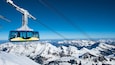 A cable car with a clear view of snow-covered mountains and a blue sky.