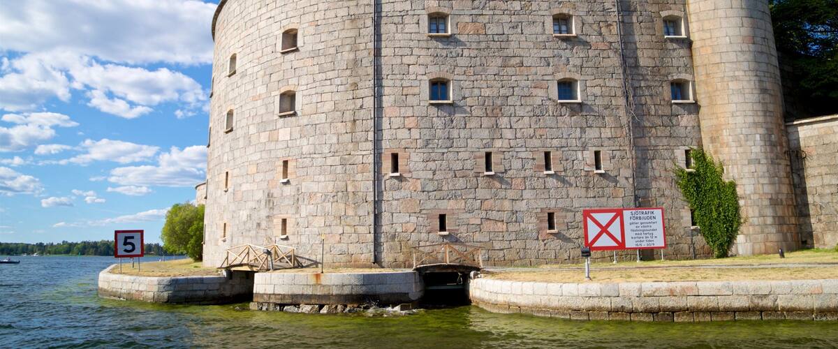 A stone tower by a lake with a speed limit sign and a no entry sign.