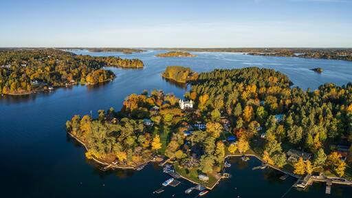 Une vue aérienne d’un lac entouré de forêts denses et de plusieurs îles, avec un imposant bâtiment blanc qui se dresse sur l’une de ces îles.