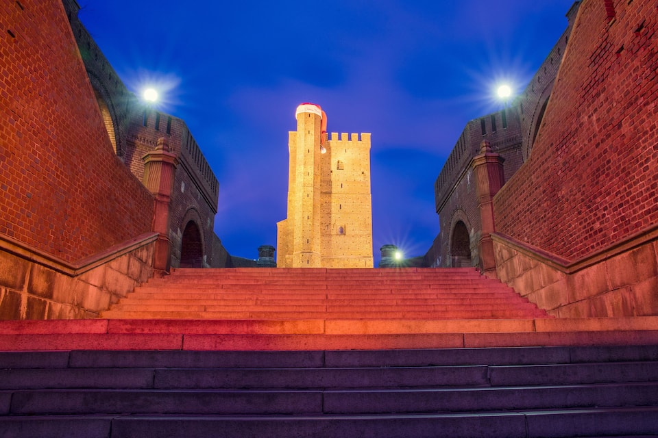 A historic tower with a staircase leading up to it, surrounded by brick walls.