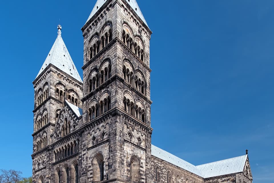 A large, historic stone building with two prominent towers and a large central entrance.
