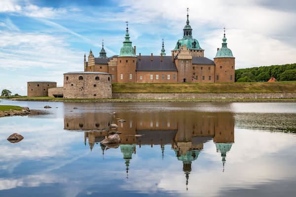 Kalmar Castle on a quiet summer morning with reflection in the calm water in the foreground.