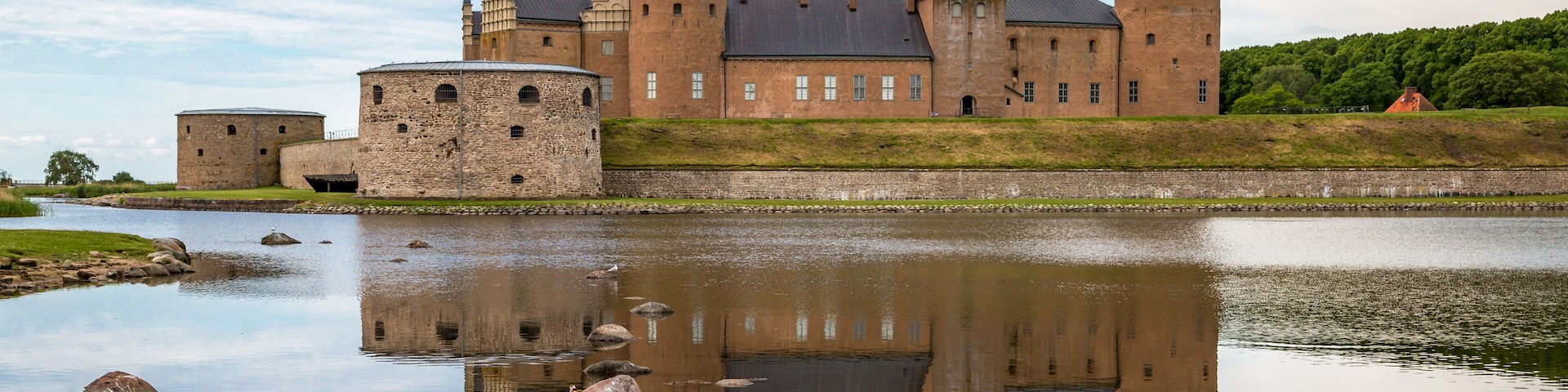 Kalmar Castle on a quiet summer morning with reflection in the calm water in the foreground.